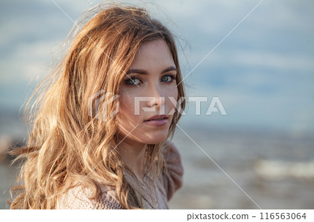 Glorious young adult female model with windy brown hair walking outdoor 116563064