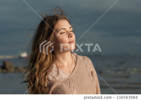 Carefree young adult female model with windy brown hair walking outdoor Carefree young adult female model with windy brown hair walking outdoor 116563068