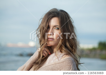 Glamorous young adult female model with windy brown hair walking outdoor Glamorous young adult female model with windy brown hair walking outdoor 116563069