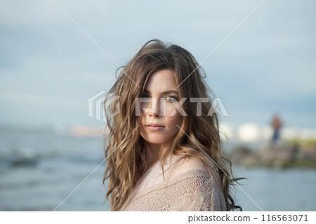 Resting young adult female model with windy brown hair walking outdoor Resting young adult female model with windy brown hair walking outdoor 116563071