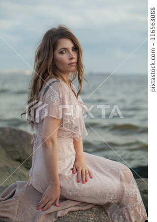 Cute young adult female model with windy brown hair walking outdoor 116563088