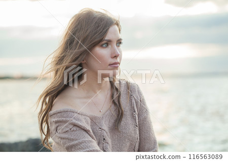 Beautiful face of young adult female model with windy brown hair walking outdoor Beautiful face of young adult female model with windy brown hair walking outdoor 116563089