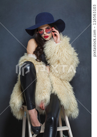 Sensual young brunette lady with makeup and long curly hair posing 116563103