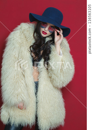 Attractive young brunette lady with makeup and long curly hair posing Attractive young brunette lady with makeup and long curly hair posing 116563105