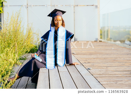 A graduate of bachelor of science. Portrait of female student in cap and gown graduation costume, holding diploma Study, education, university, college, graduate concept. 116563928