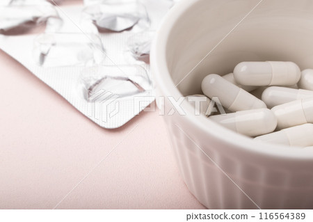 Pills on pink background closeup. White capsules, white pills, empty pills blister. Allergy pill, antibiotics, supplements. Medicine, healthcare concept. Virus(viral), flu diseases. High quality photo 116564389