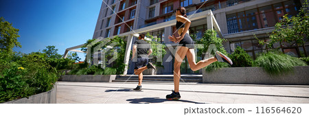 Banner. Low angle vie of couple, man and woman mid-run in city environment running across, emphasizing energy and intensity of their workout. Banner. Low angle vie of couple, man and woman mid-run in city environment running across, emphasizing energy and intensity of their workout. 116564620