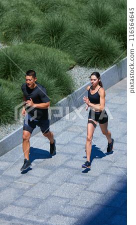 Friends, man and woman, training together outdoors. Motivation for healthy lifestyle. Beautiful and comfy jogging uniform. Friends, man and woman, training together outdoors. Motivation for healthy lifestyle. Beautiful and comfy jogging uniform. 116564645