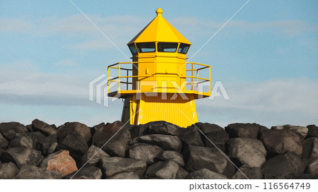 Yellow lighthouse tower standing at the breakwater. Iceland 116564749