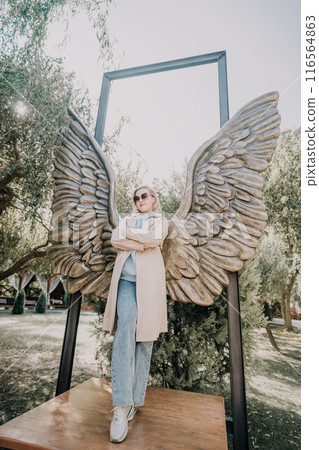 Woman Posing with Angel Wings Sculpture 116564863