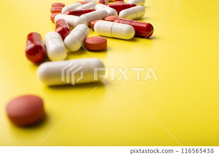 Pills closeup. Medical pills and capsules. Isolated on yellow background. Vitamins, supplements, antibiotics, allergy pill. Medicine, healthcare concept. Virus and flu diseases. High quality photo Pills closeup. Medical pills and capsules. Isolated on yellow background. Vitamins, supplements, antibiotics, allergy pill. Medicine, healthcare concept. Virus and flu diseases. High quality photo 116565438