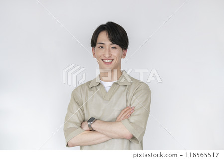 Smiling young man looking at camera with arms crossed 116565517
