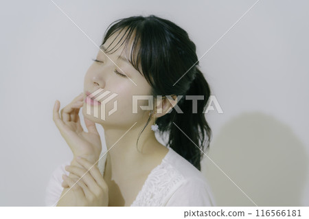 Portrait of a young woman bathed in sunlight against a white background Portrait of a young woman bathed in sunlight against a white background 116566181