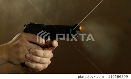 Man Shooting a Pistol on Dark Background , Close-up . 116566299