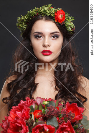 Charming young woman with floral head wreath looking at camera 116566490