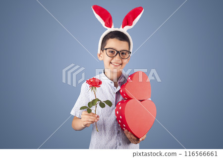 cute boy with gifts and flowers for a party. studio photo on the blue background cute boy with gifts and flowers for a party. studio photo on the blue background 116566661