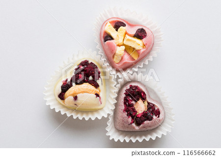 chocolate sweets in the form of a heart with fruits and nuts on a colored background. top view with space for text, holiday concept 116566662