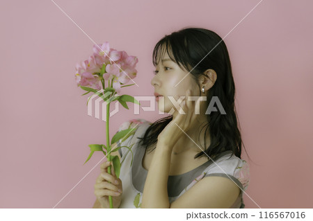 Portrait of a young woman with flowers on a pink background Portrait of a young woman with flowers on a pink background 116567016
