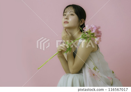 Portrait of a young woman with flowers on a pink background Portrait of a young woman with flowers on a pink background 116567017
