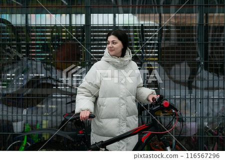 Woman in White Coat Walking Her Bike Woman in White Coat Walking Her Bike 116567296