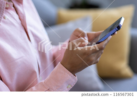 Person using smartphone at home on sofa. Casual attire adds relaxed feel to image that emphasizes connection, technology, and communication. Ideal for representing concepts like home life Person using smartphone at home on sofa. Casual attire adds relaxed feel to image that emphasizes connection, technology, and communication. Ideal for representing concepts like home life 116567301