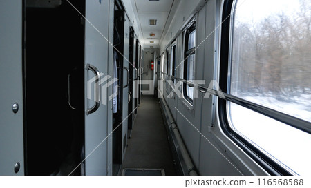 Corridor in the compartment of the Intercity train. Winter snowy landscapes float past the windows. Corridor in the compartment of the Intercity train. Winter snowy landscapes float past the windows. 116568588