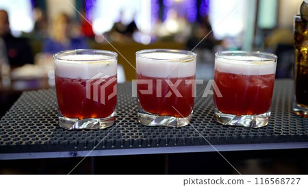 Glasses with an alcoholic cocktail, 3 pieces, stand on the bar counter, close-up. Glasses with an alcoholic cocktail, 3 pieces, stand on the bar counter, close-up. 116568727