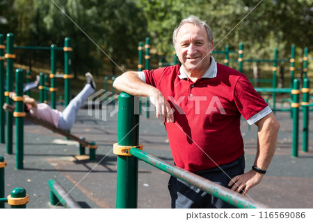 Elderly man stands in a sports bar on an outdoor sports field 116569086