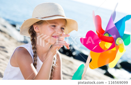Girl with windmill on sea in summer 116569099