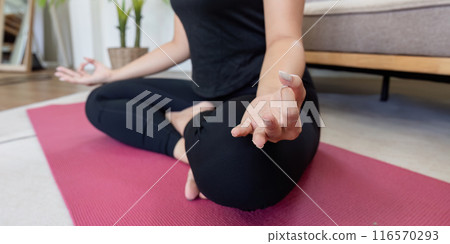 Woman Practicing Yoga Indoors on a Pink Mat in a Relaxing Home Environment 116570293