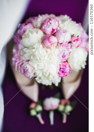 Pair of elegant and stylish bridal shoes with a bouquet with roses and other flowers 116570360