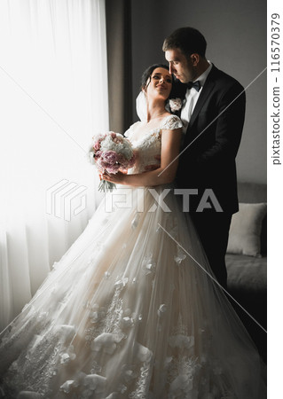 Romantic wedding moment, couple of newlyweds smiling portrait, bride and groom hugging 116570379