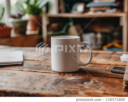 A white mug sitting on a vintage aged rosewood desk with various modern office supplies organized around it.  116571800