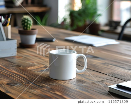 A white mug sitting on a vintage aged rosewood desk with various modern office supplies organized around it.  116571809