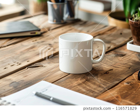 A white mug sitting on a vintage aged rosewood desk with various modern office supplies organized around it.  116571829
