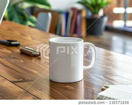 A white mug sitting on a vintage aged rosewood desk with various modern office supplies organized around it.  116571830