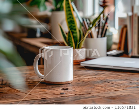 A white mug sitting on a vintage aged rosewood desk with various modern office supplies organized around it.  116571831