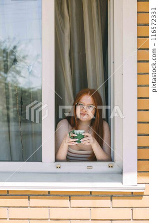 efficiency and novelty of a robotic window cleaner as it effortlessly glides over glass surfaces, while the girl is drinking tea efficiency and novelty of a robotic window cleaner as it effortlessly glides over glass surfaces, while the girl is drinking tea 116572331