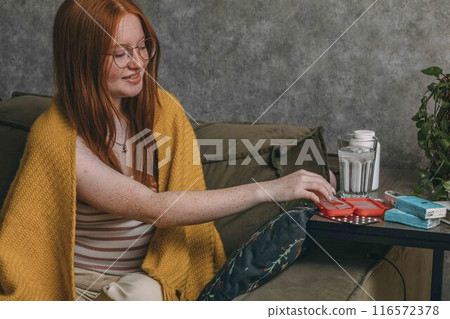 young woman sorting her medications at home, highlighting personal responsibility in health care young woman sorting her medications at home, highlighting personal responsibility in health care 116572378