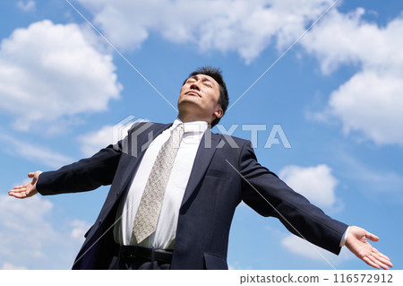 一個穿著西裝的男人，雙臂張開，閉著眼睛 116572912