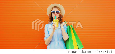 Fashion portrait of beautiful young woman with colorful shopping bags drinking juice in summer hat 116573141