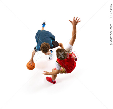 Basketball player in blue tries to outmaneuver defender in red, encapsulating thrill of game against white studio background. Aerial view. 116573487