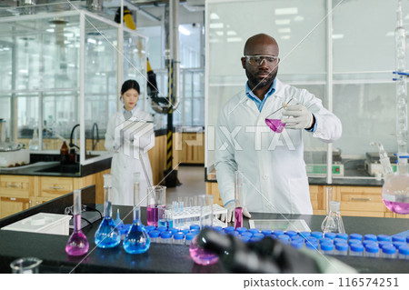 Man studying purple liquid substance Man studying purple liquid substance 116574251