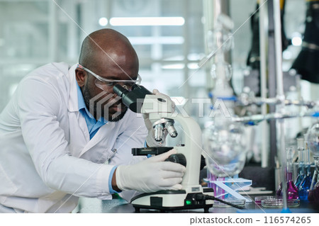 Looking in microscope during research Looking in microscope during research 116574265