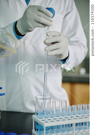 Man dropping liquid through glass pipe Man dropping liquid through glass pipe 116574300