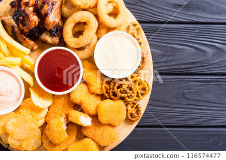 Onion rings , nuggets grilled wings , french fries mix of snacks and sauces . Beer board 116574477