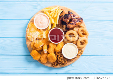 Onion rings , nuggets grilled wings , french fries mix of snacks and sauces . Beer board 116574478