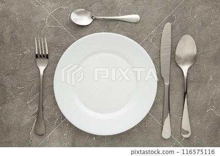 Table setting with white plates, and cutlery - fork, spoon and knife. Shot from above. Copy space on empty plate. Table setting with white plates, and cutlery - fork, spoon and knife. Shot from above. Copy space on empty plate. 116575116