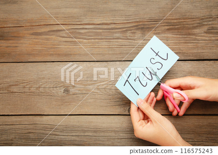 Scissors cutting paper with word TRUST on grey background. Concept of jealousy 116575243