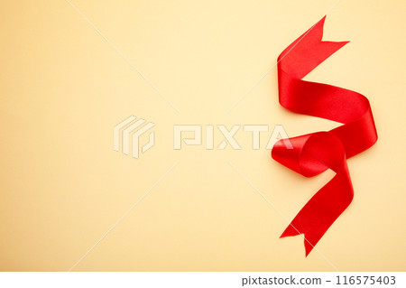 Shiny red ribbon on beige background with copy space. 116575403